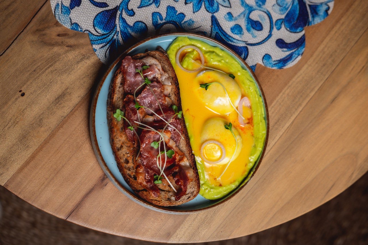 Avocado and bacon toast on blue plate